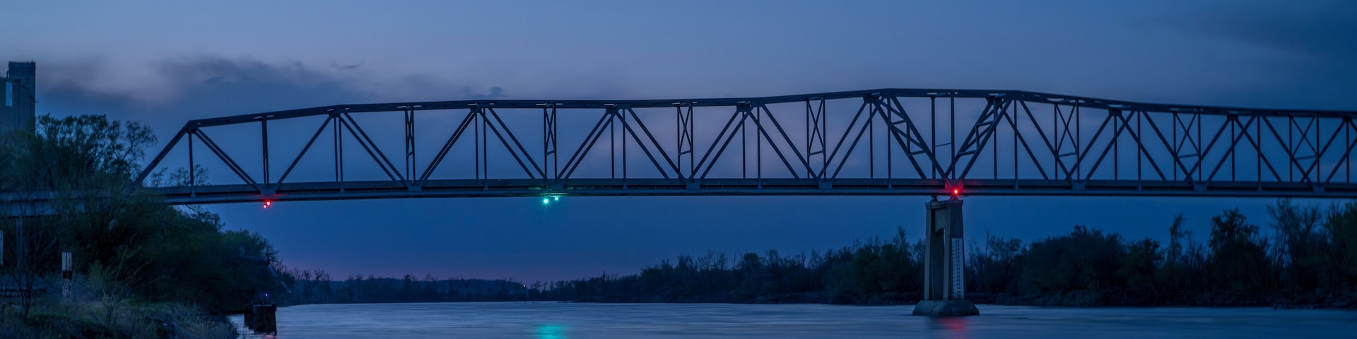 Uma ponte sobre um rio calmo ao anoitecer.