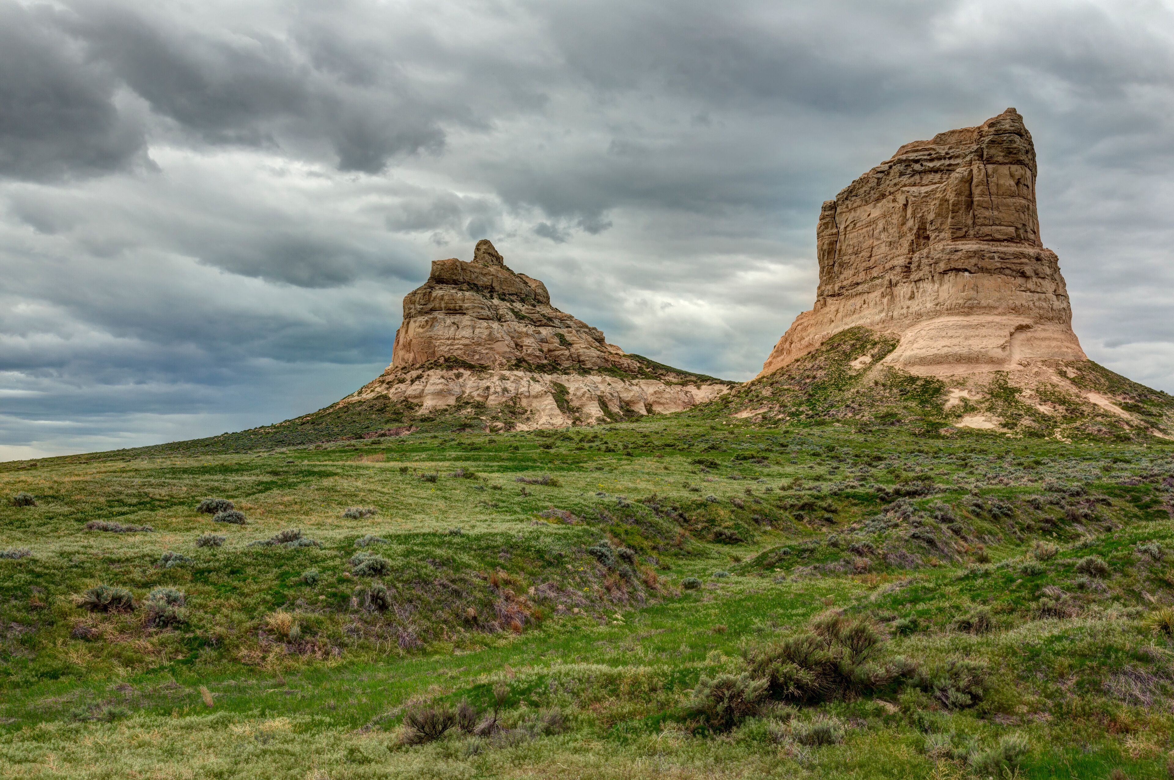 A landscape with two prominent rock formations under a cloudy sky.