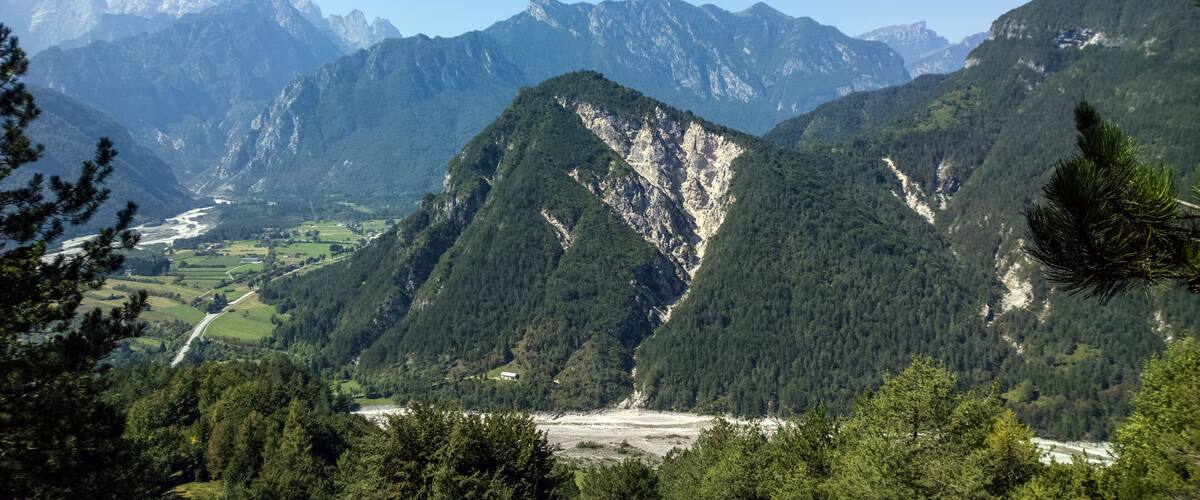 A mountainous landscape with a valley, dense forests, and a river.