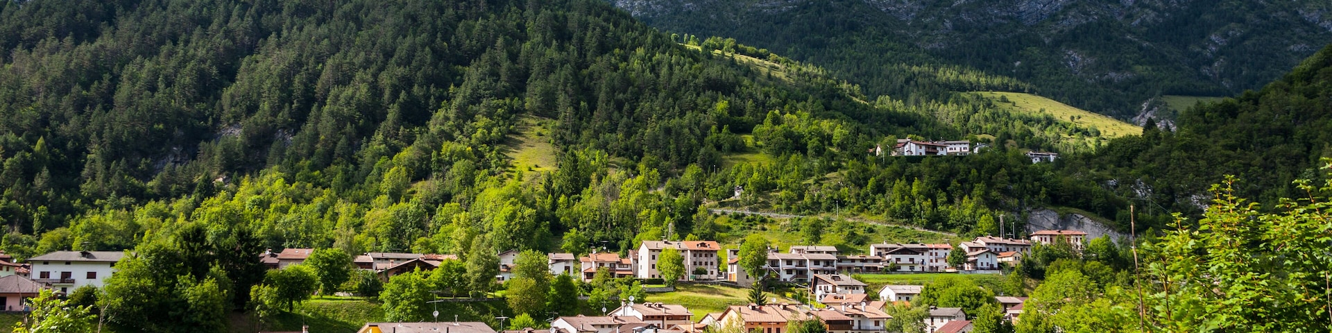 Un paisaje montañoso con un pueblo ubicado entre verdes colinas y árboles.