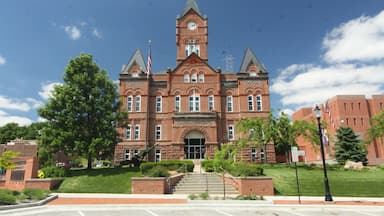 A large brick building with a clock tower, surrounded by trees and a clear blue sky.