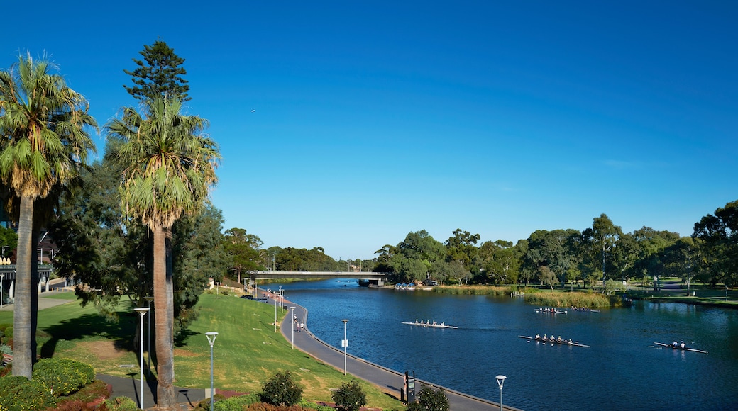 A river with boats, a bridge, and a park with trees and a pathway.