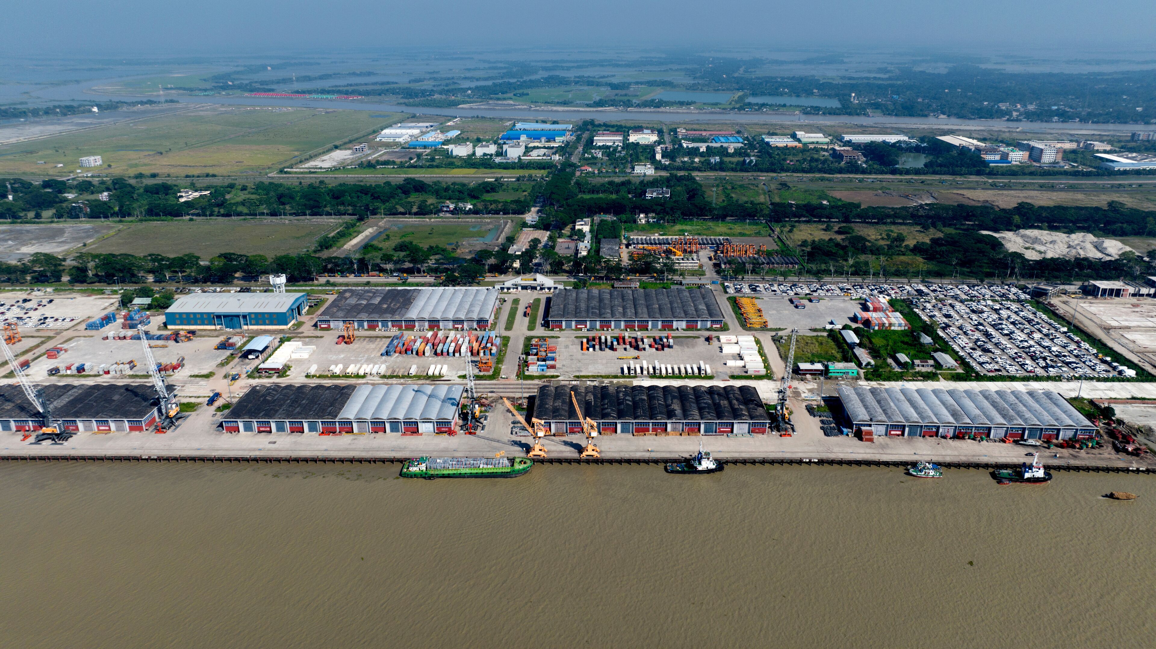An industrial area with warehouses, a large parking lot, and a river.
