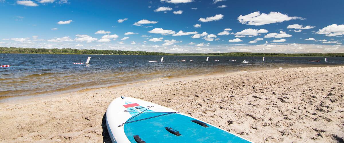A beach with a kayak and several boats on the water.