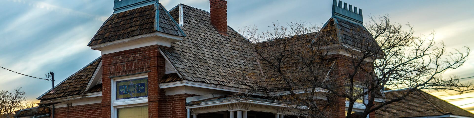 A Victorian-style building with a brick facade, a gabled roof, and decorative chimneys.