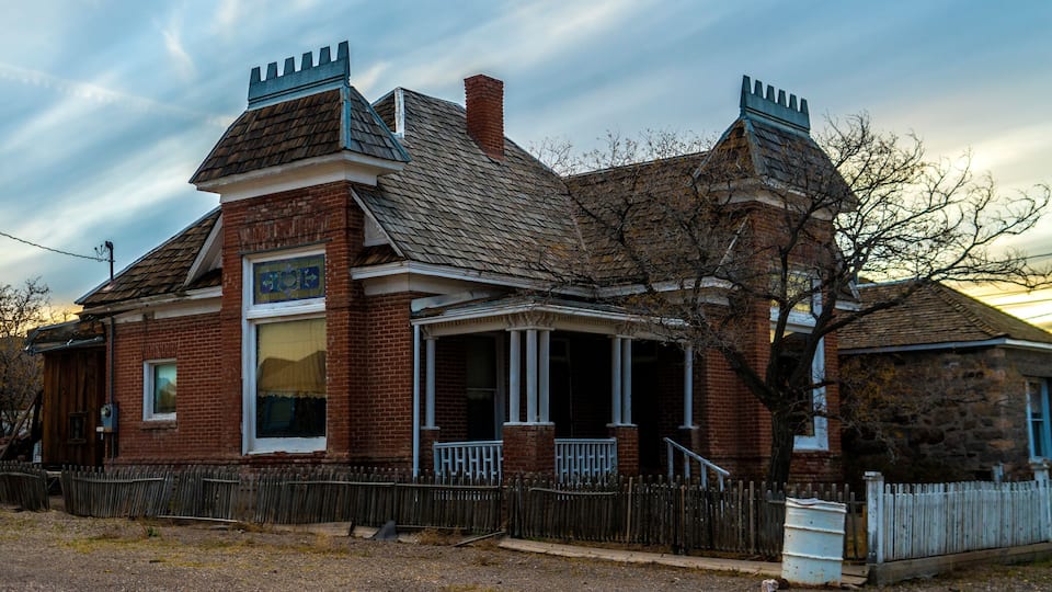 A Victorian-style building with a brick facade, a gabled roof, and decorative chimneys.