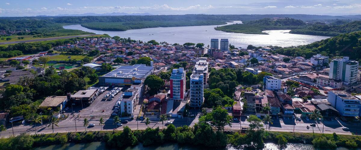 A coastal cityscape with a river, buildings, and greenery.