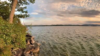 A lake with a sunset, surrounded by trees and rocks.
