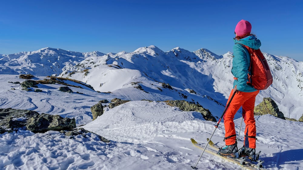 Mature woman with back pack skiing on snowcapped Kastenwendenkopf, Kitzbuehel Alps, Tyrol, Austria