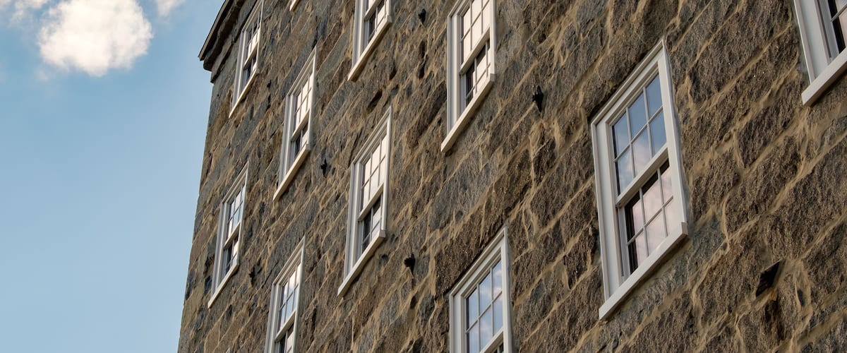 A stone building with multiple windows and a clear sky with clouds.