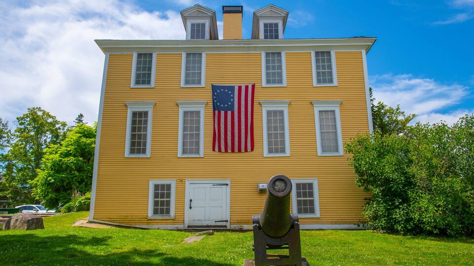 A yellow building with an American flag and a cannon in front.
