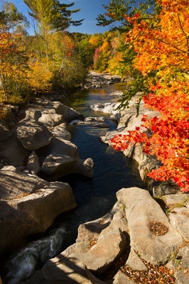 A river flowing through a rocky landscape with autumn foliage.