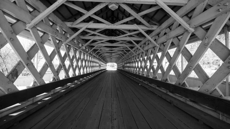 A wooden pedestrian bridge with a lattice roof structure.