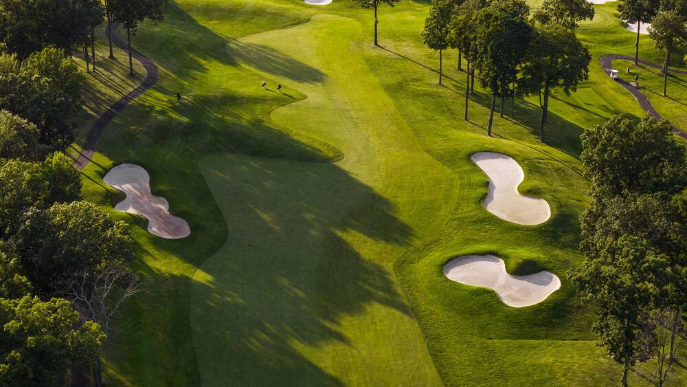 Un parcours de golf avec des bunkers de sable et des arbres.