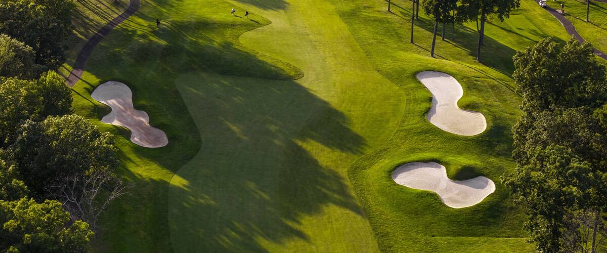 A golf course with sand bunkers and trees.