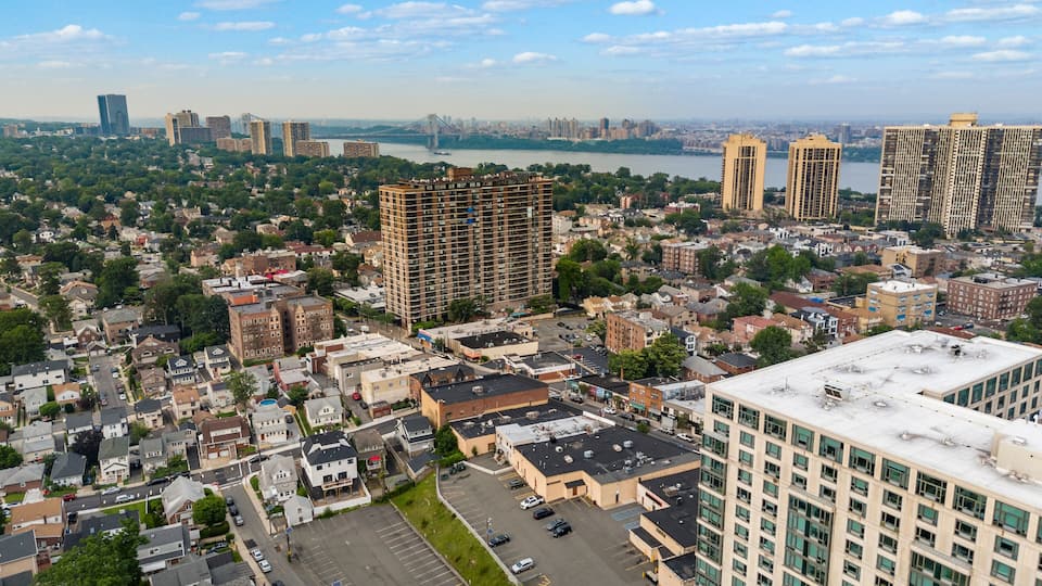 A cityscape with a mix of residential and commercial buildings, a river, and a bridge in the background.