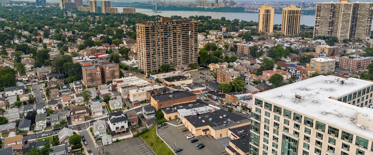 A cityscape with a mix of residential and commercial buildings, a river, and a bridge in the background.