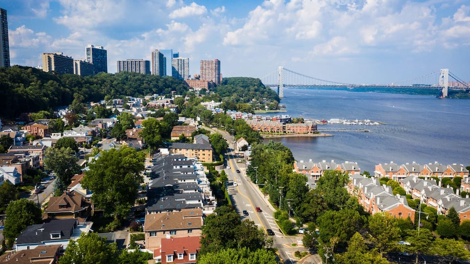 A coastal cityscape with residential areas, a prominent bridge, and high-rise buildings.