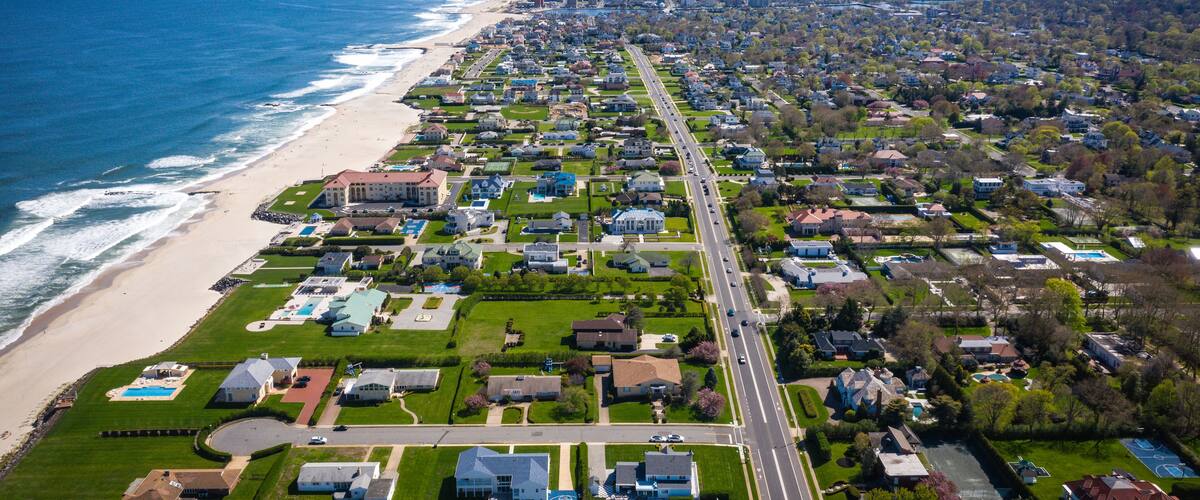 A coastal residential area with a beach, houses, and a road.
