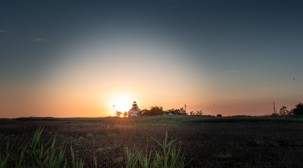 A distant shot of the sunset with the East Point Lighthouse.