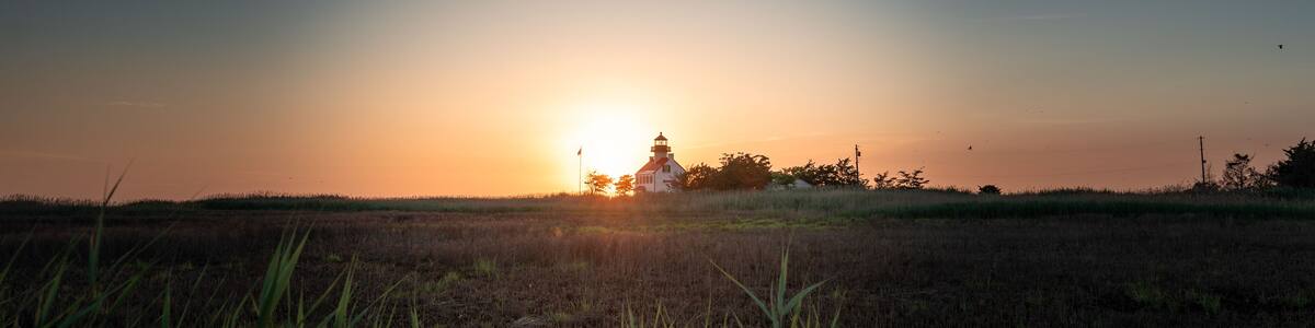 A distant shot of the sunset with the East Point Lighthouse.