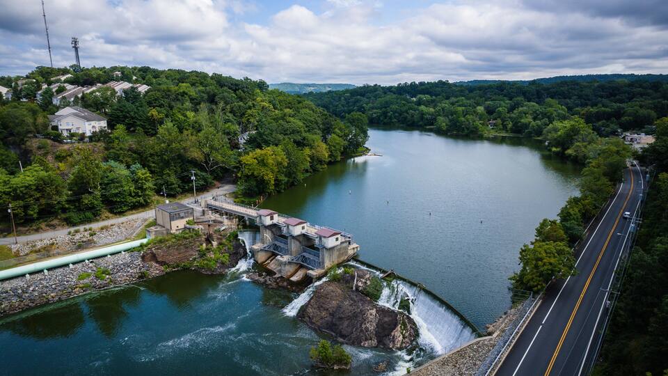 A river with a dam and a road alongside it.