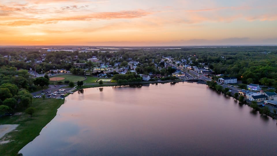 A lakeside town at sunset with a bridge connecting two parts of the town.