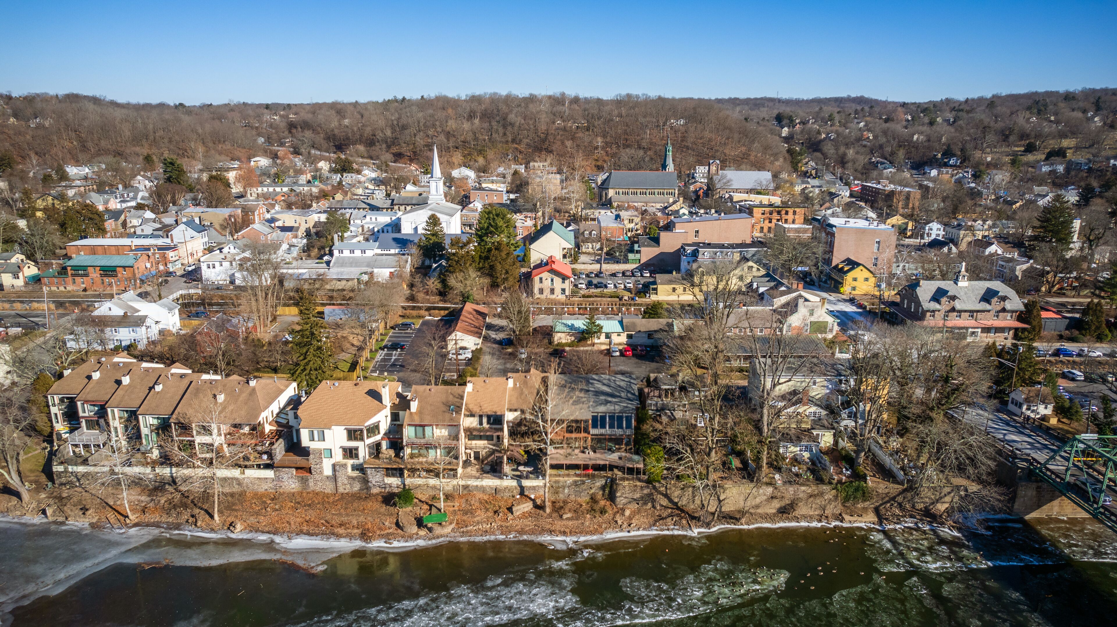 A town with a river, buildings, and a hill in the background.