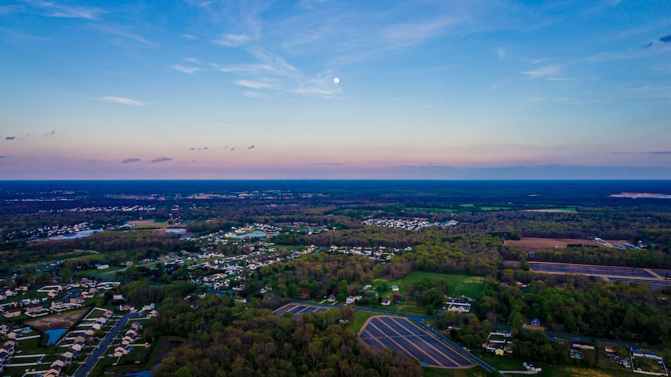 A rural landscape with residential areas, fields, and a large body of water.