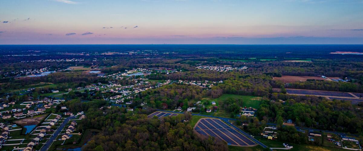 A rural landscape with residential areas, fields, and a large body of water.