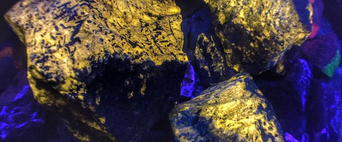 Three large, rough-textured rocks with a golden hue, illuminated by blue lighting.