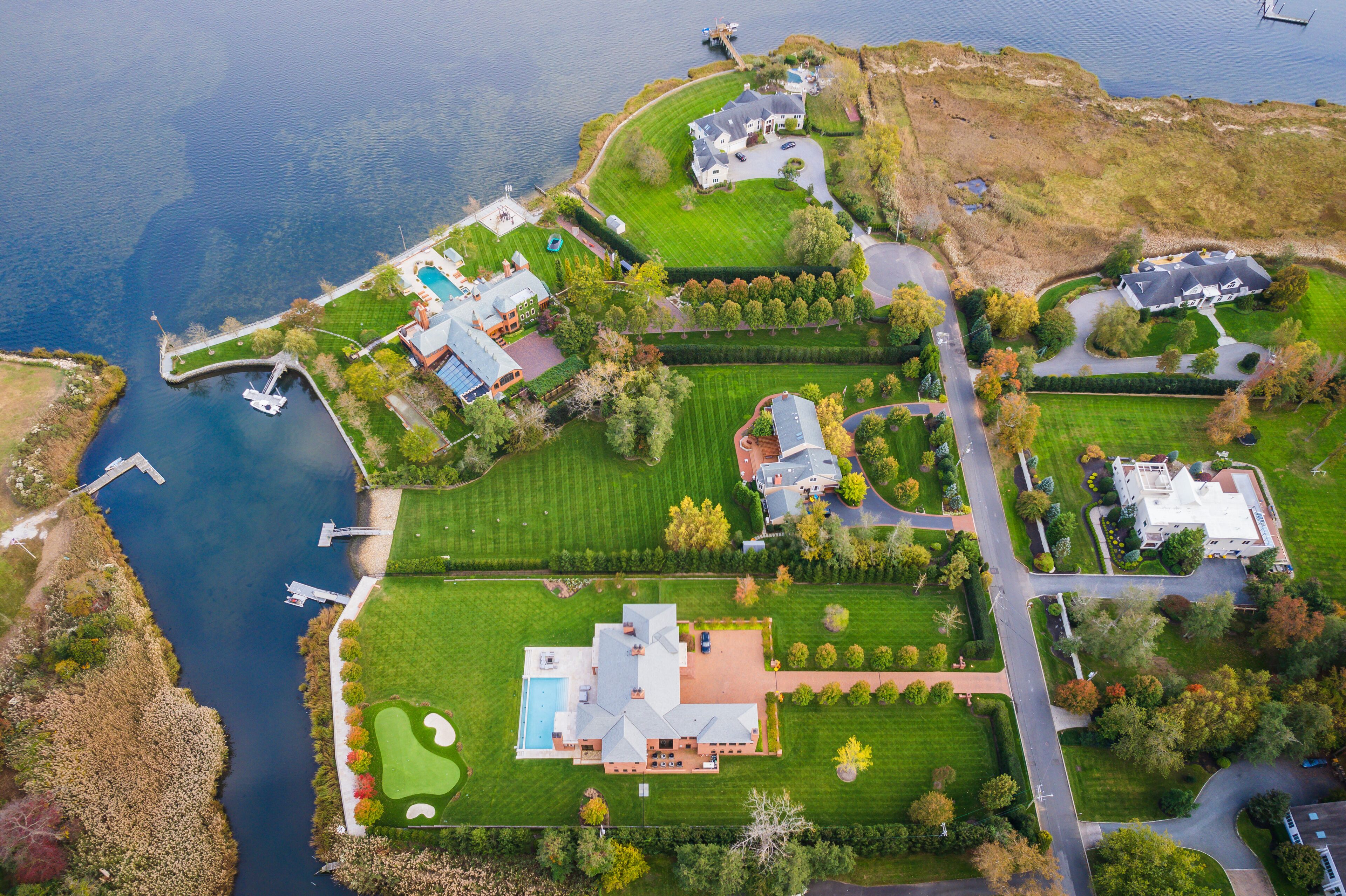 An aerial view of a lakeside property with multiple houses, a dock, and a golf course.