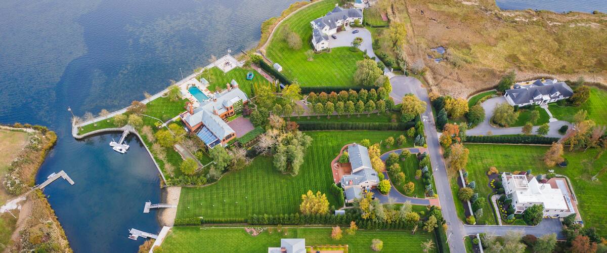 An aerial view of a lakeside property with multiple houses, a dock, and a golf course.