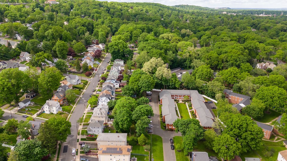 An aerial view of a residential area with houses, streets, and surrounding greenery.