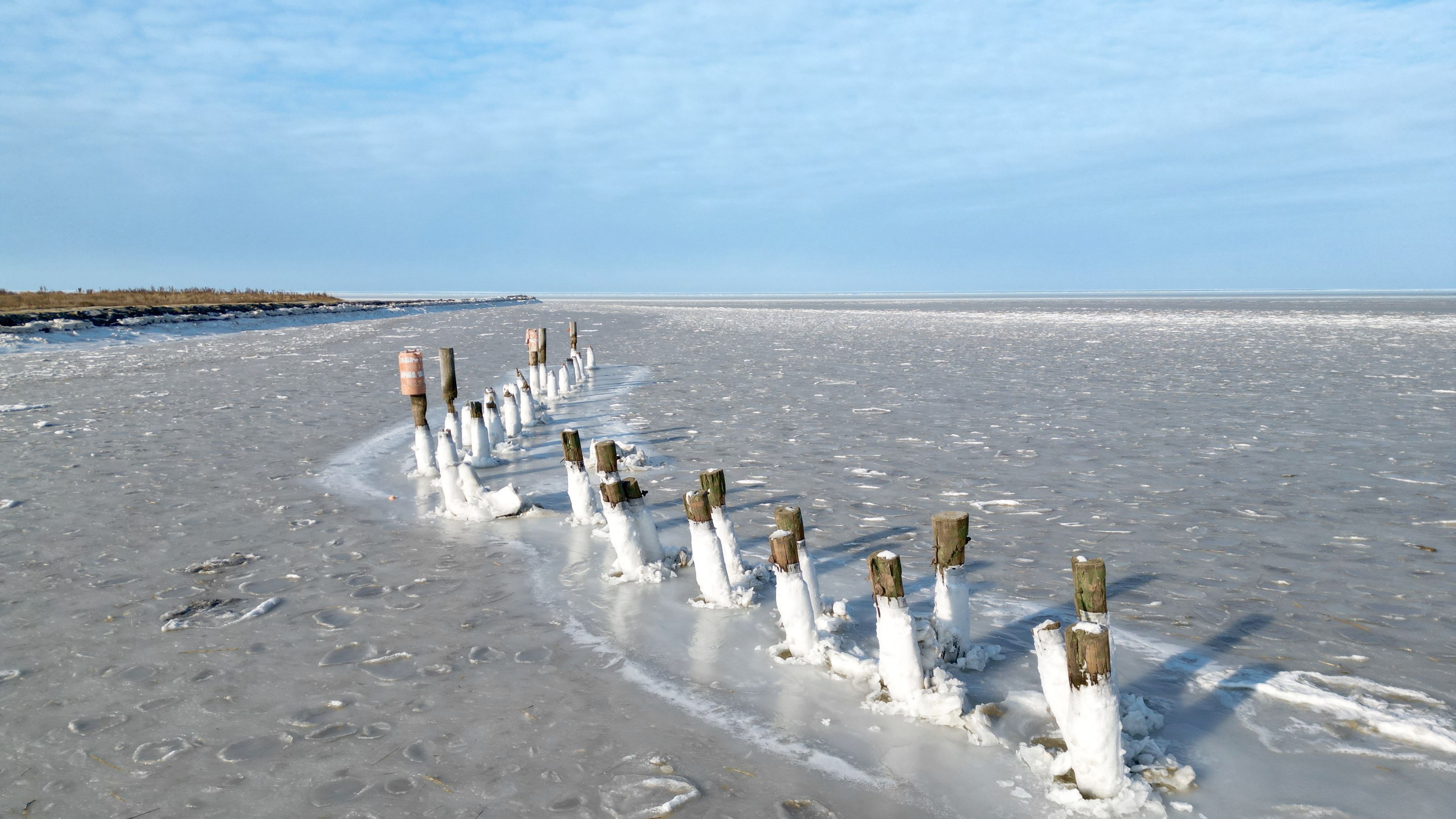 A frozen landscape with wooden posts and footprints in the snow.