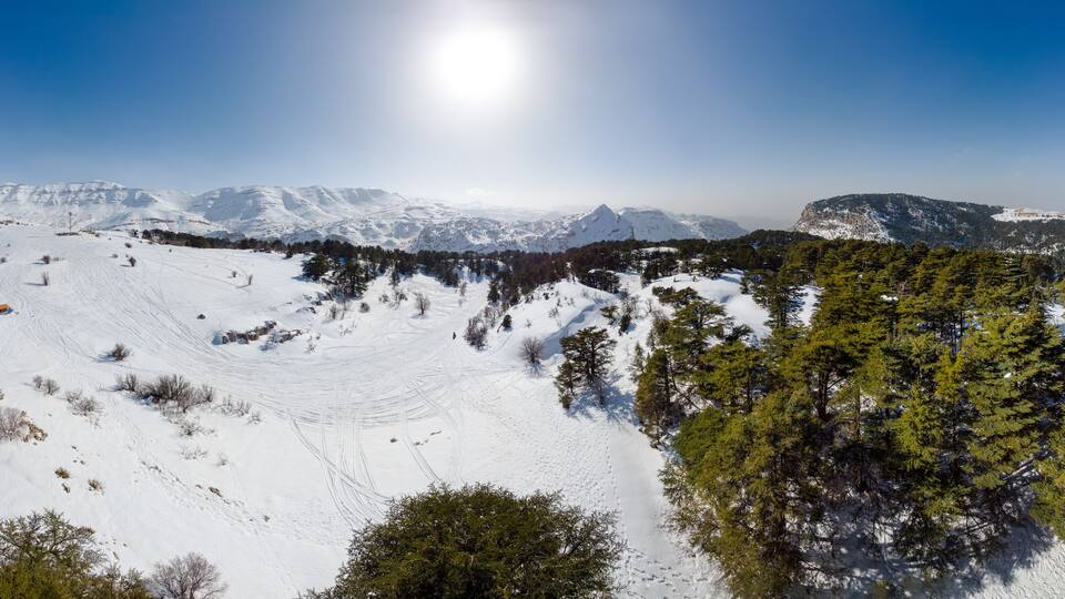 A snow-covered mountain landscape with clear skies and a bright sun.