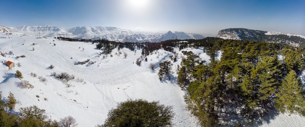 A snow-covered mountain landscape with clear skies and a bright sun.