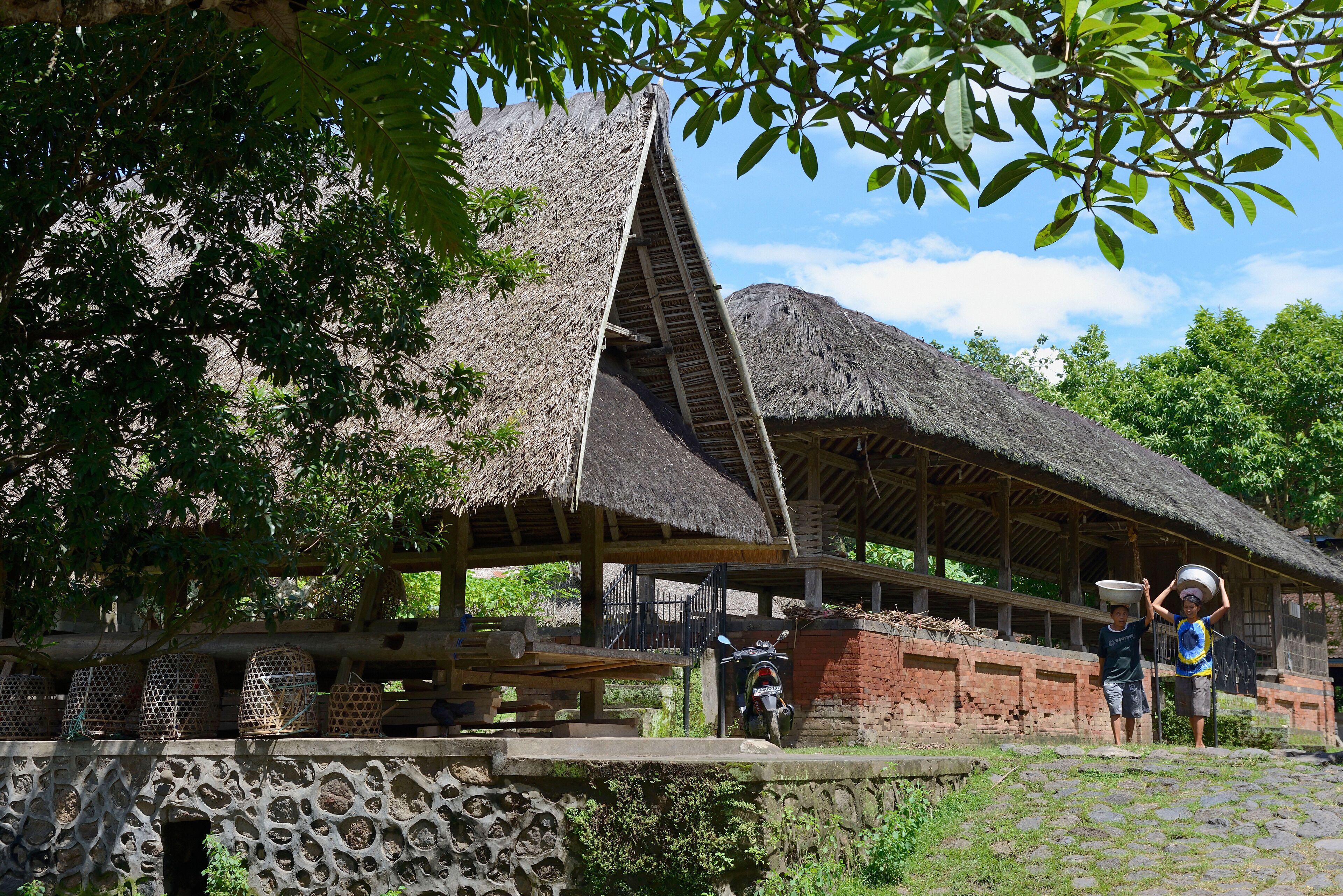 A traditional thatched-roof structure with a stone wall and a staircase leading up to it.