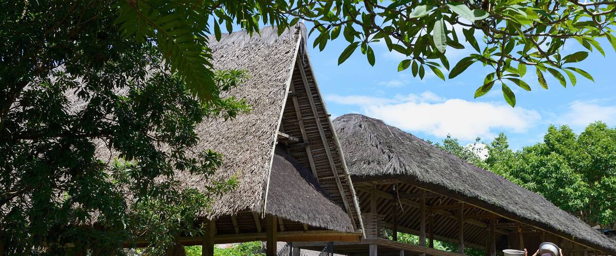A traditional thatched-roof structure with a stone wall and a staircase leading up to it.