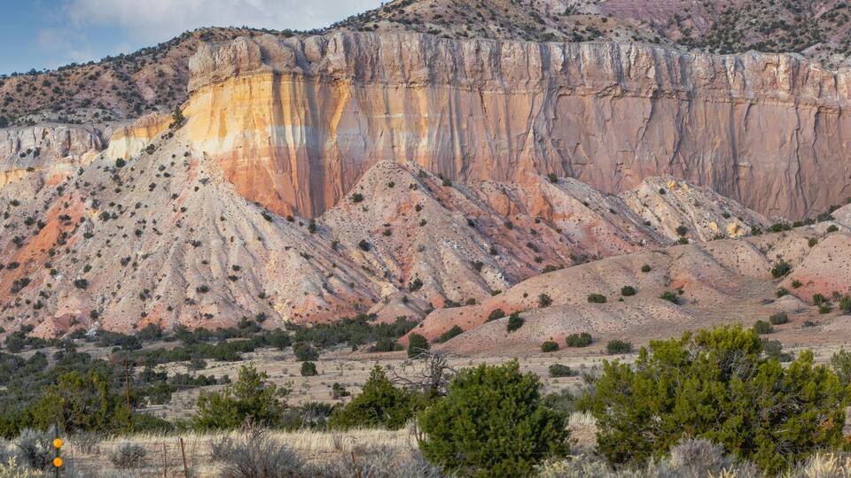 A rugged mountain landscape with layered rock formations and sparse vegetation.