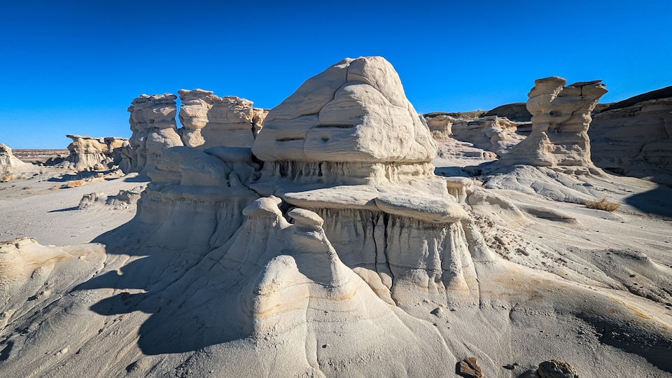 A desert landscape with prominent rock formations and a clear blue sky.