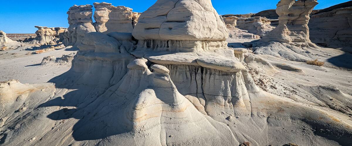 A desert landscape with prominent rock formations and a clear blue sky.