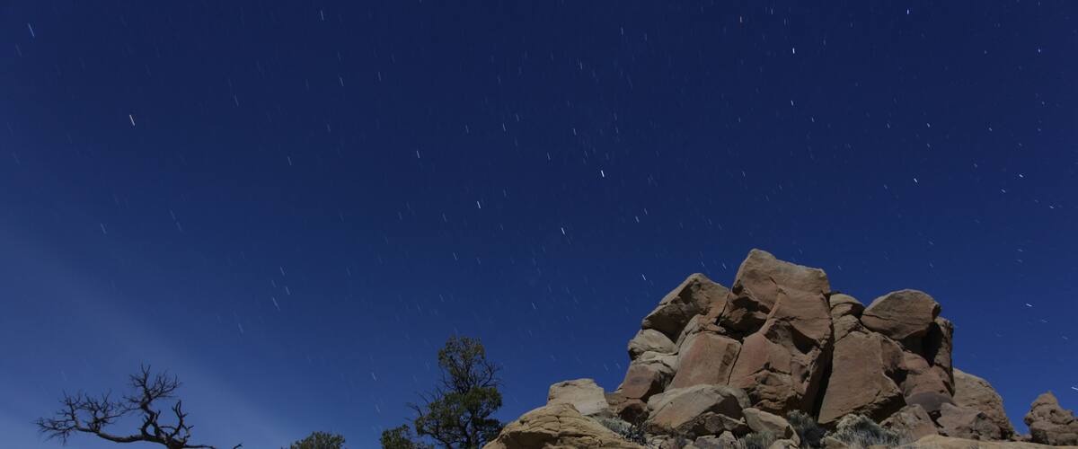A rocky landscape with a clear night sky and stars.
