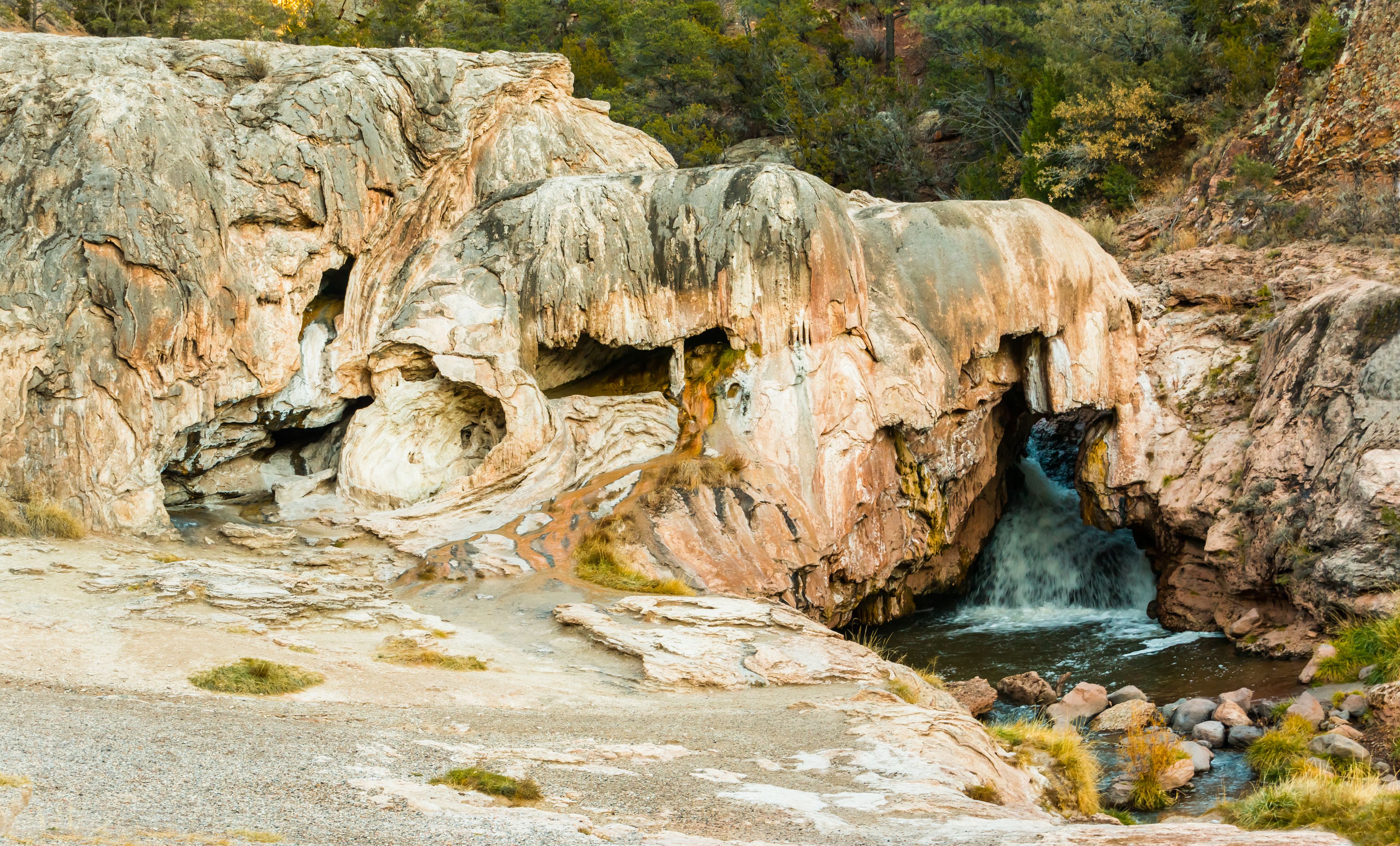 Un paisaje rocoso con una cascada que fluye a través de una cueva.