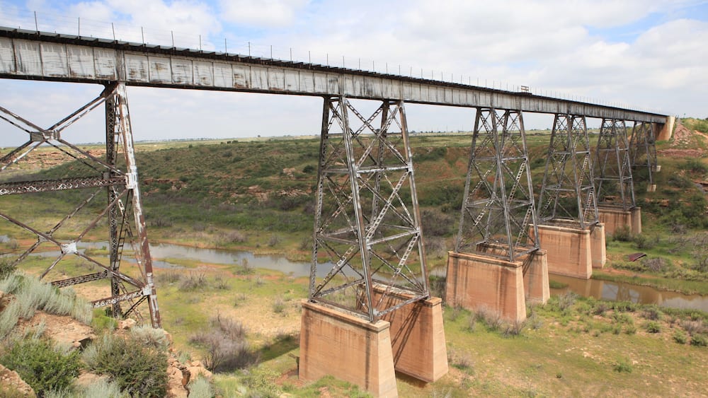 A large metal bridge with multiple supports spanning a river.