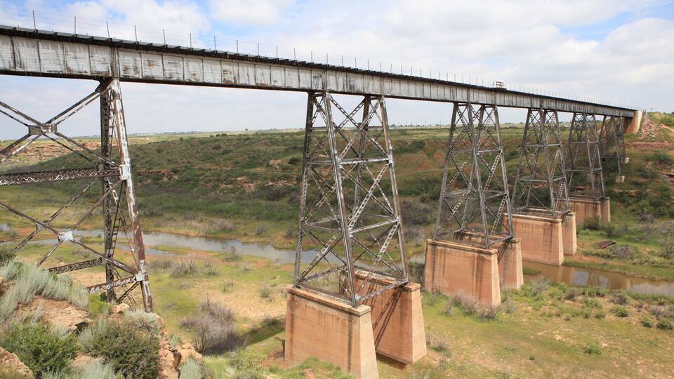 A large metal bridge with multiple supports spanning a river.
