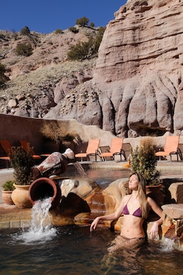 Ojo Caliente, New Mexico, United States. Woman relaxing outdoors in a mineral pool for health and wellness.
