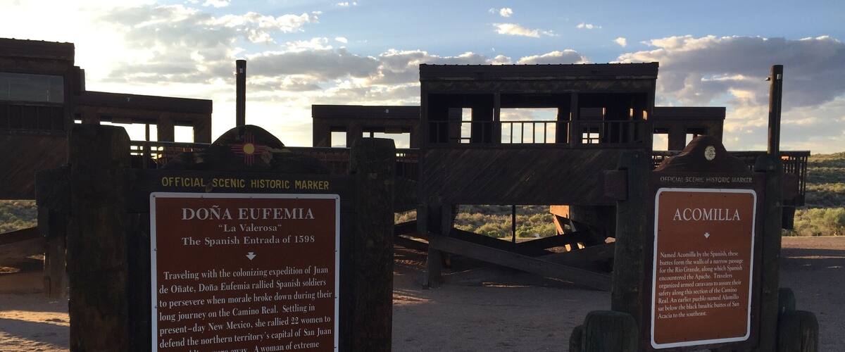 Two wooden structures with historical markers, one labeled Dona Eufemia and the other Acomilla, set against a clear sky.