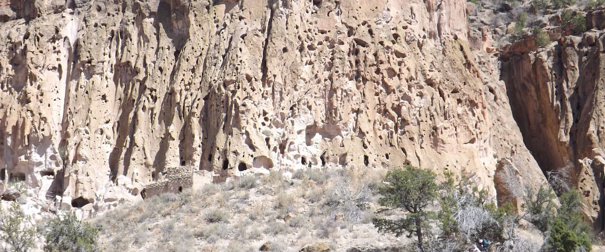 A rugged canyon with layered rock formations and sparse vegetation.