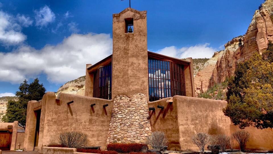 A church with a bell tower, stone walls, and a cross.
